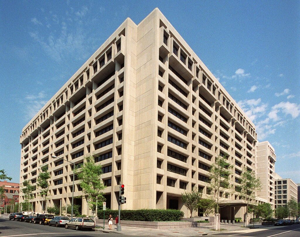 The International Monetary Fund headquarters building in Washington, DC, under a clear blue sky.