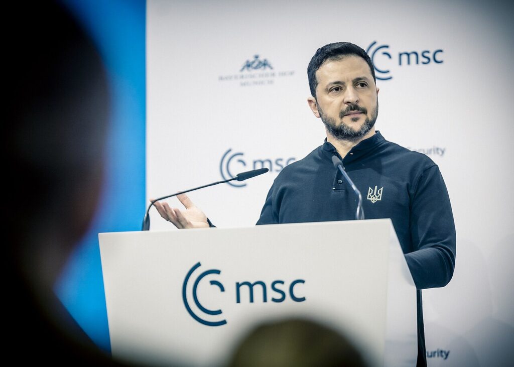 Volodymyr Zelensky speaking at the Munich Security Conference podium, with the MSC logo behind him