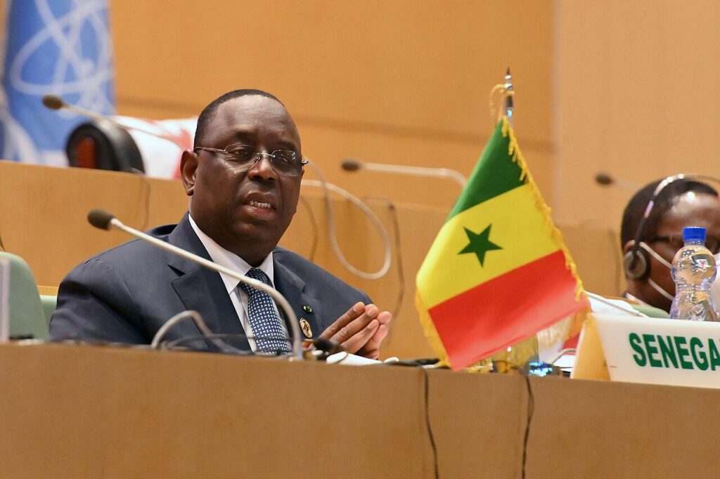 Former Senegalese president Macky Sall speaking into a microphone at a conference table