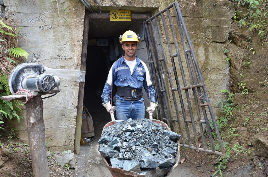 A Colombian gold miner pushes a wheelbarrow of ore out of a mine shaft.