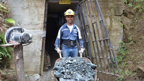 A Colombian gold miner pushes a wheelbarrow of ore out of a mine shaft.