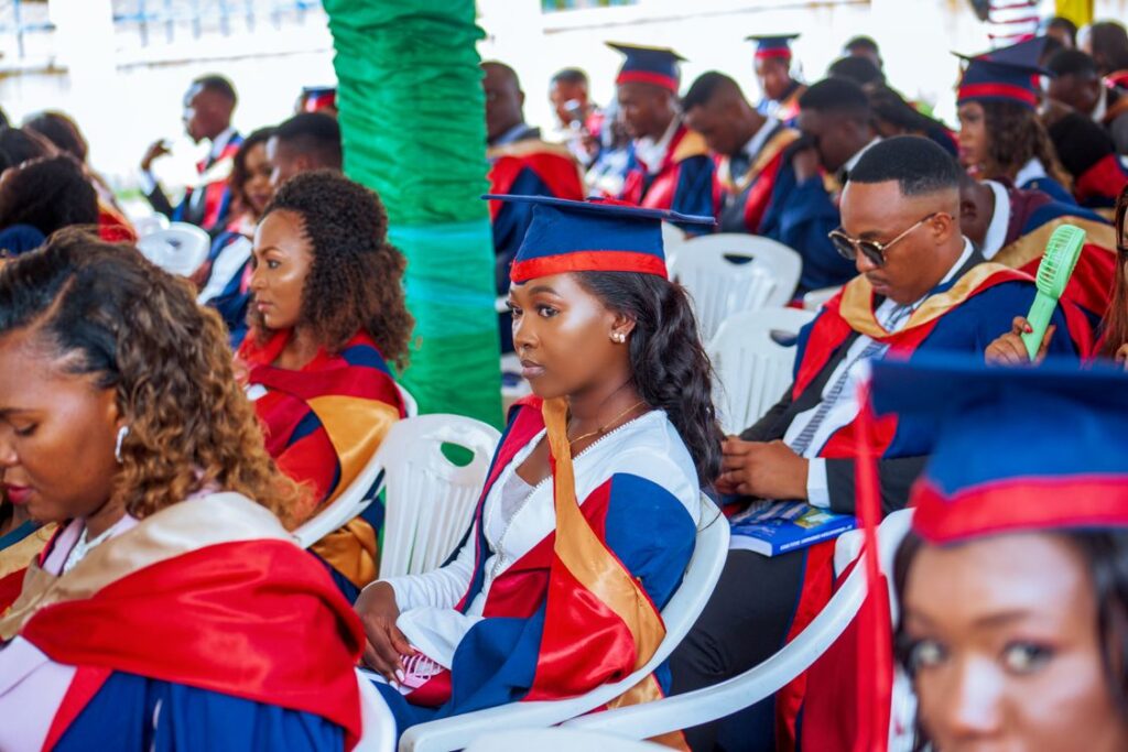 Diverse graduates in caps and gowns sitting at a graduation ceremony