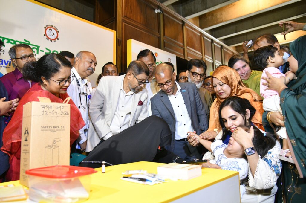 Bangladeshi health officials watch as a child is vaccinated during the measles-rubella campaign in Dhaka