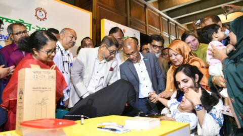 Bangladeshi health officials watch as a child is vaccinated during the measles-rubella campaign in Dhaka