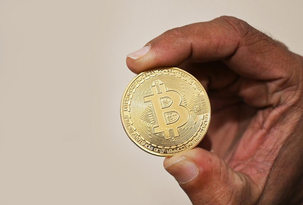 A hand holding a physical bitcoin coin.
