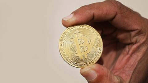 A hand holding a physical bitcoin coin.