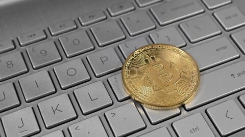 A physical Bitcoin coin resting on a laptop keyboard
