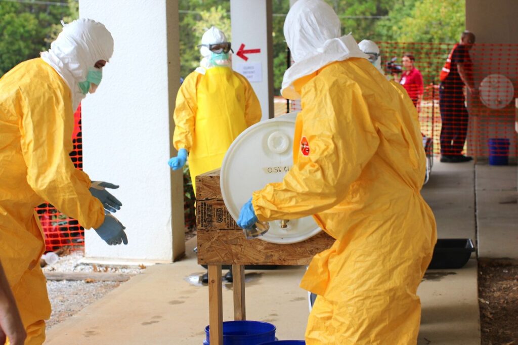Health workers in yellow protective suits outdoors during an outbreak-response training exercise