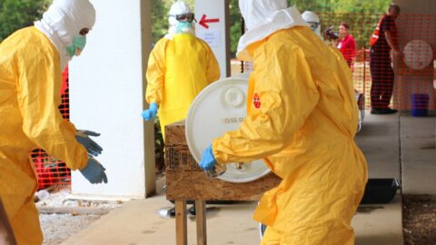 Health workers in yellow protective suits outdoors during an outbreak-response training exercise