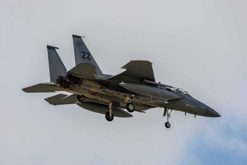An F-15 Eagle fighter jet banking in flight under a clear blue sky