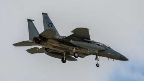 An F-15 Eagle fighter jet banking in flight under a clear blue sky