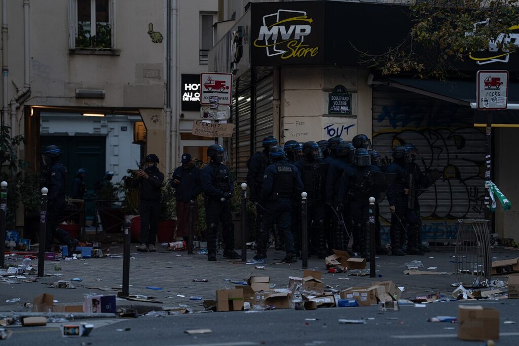 French riot police in protective gear outside a looted shop in Paris during the October 17, 2026 unrest