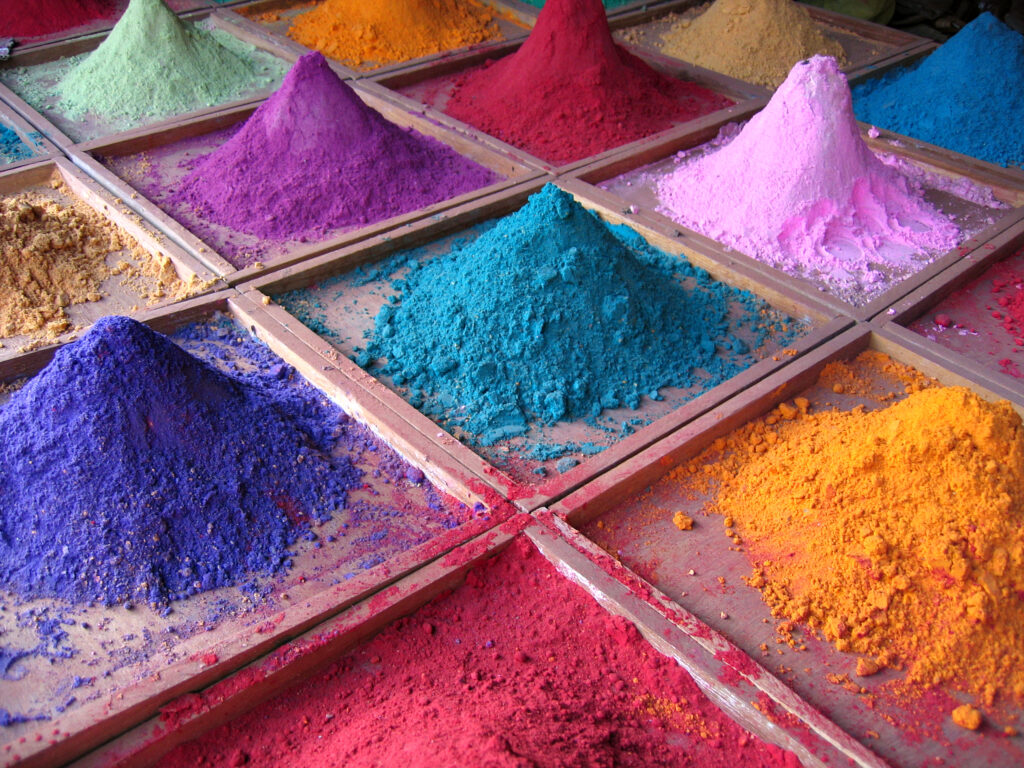 Colorful pigment powders piled in trays at a market stall