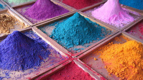 Colorful pigment powders piled in trays at a market stall