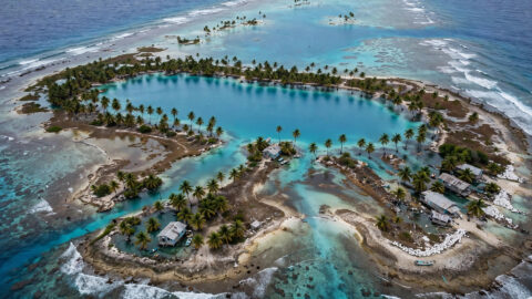 Aerial view of a Pacific coral atoll with rising seas threatening the shoreline
