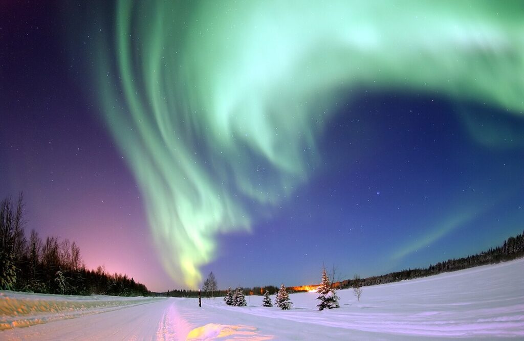 Green aurora borealis glowing over a lake in Alaska.