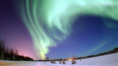 Green aurora borealis glowing over a lake in Alaska.