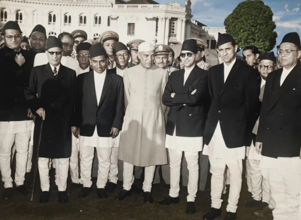 Jawaharlal Nehru, in white cap and light achkan, standing at the centre of a group of officials during a visit to Kathmandu in 1960