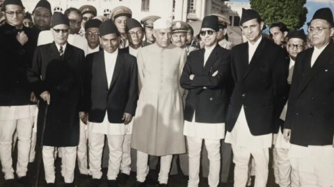 Jawaharlal Nehru, in white cap and light achkan, standing at the centre of a group of officials during a visit to Kathmandu in 1960