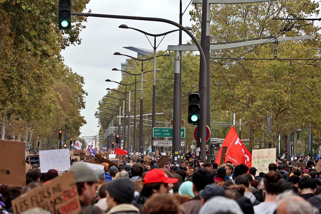 Large peaceful crowd marching through Paris carrying placards and flags during the cost-of-living protests.