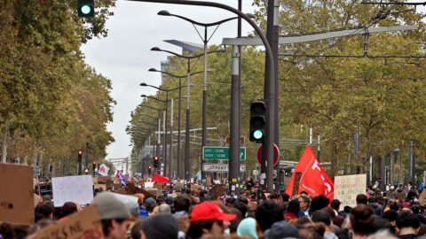 Large peaceful crowd marching through Paris carrying placards and flags during the cost-of-living protests.