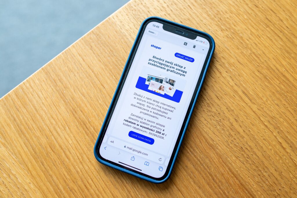 Smartphone displaying an online advertisement on a wooden surface. Photo by Shoper, via Pexels (Pexels License, free to use).