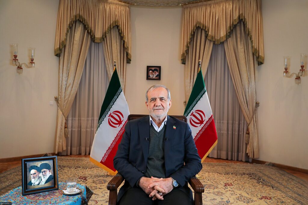 Iranian President Masoud Pezeshkian seated between two Iranian flags in a 2025 portrait.