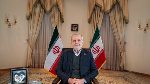 Iranian President Masoud Pezeshkian seated between two Iranian flags in a 2025 portrait.