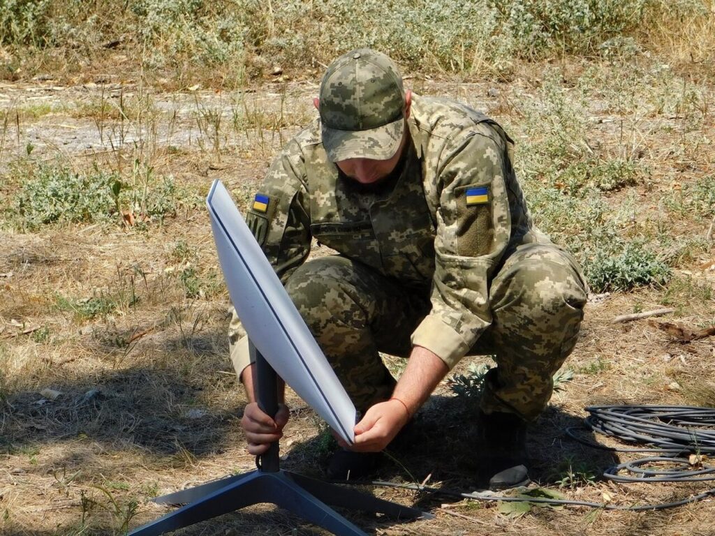 A Ukrainian soldier installs a Starlink satellite terminal in the field