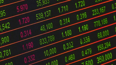 A digital stock exchange board showing flashing share prices in red and green