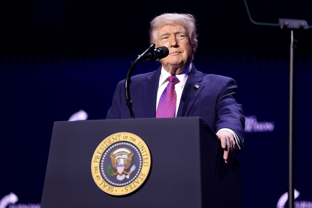 Donald Trump speaking at a rally podium with the US presidential seal