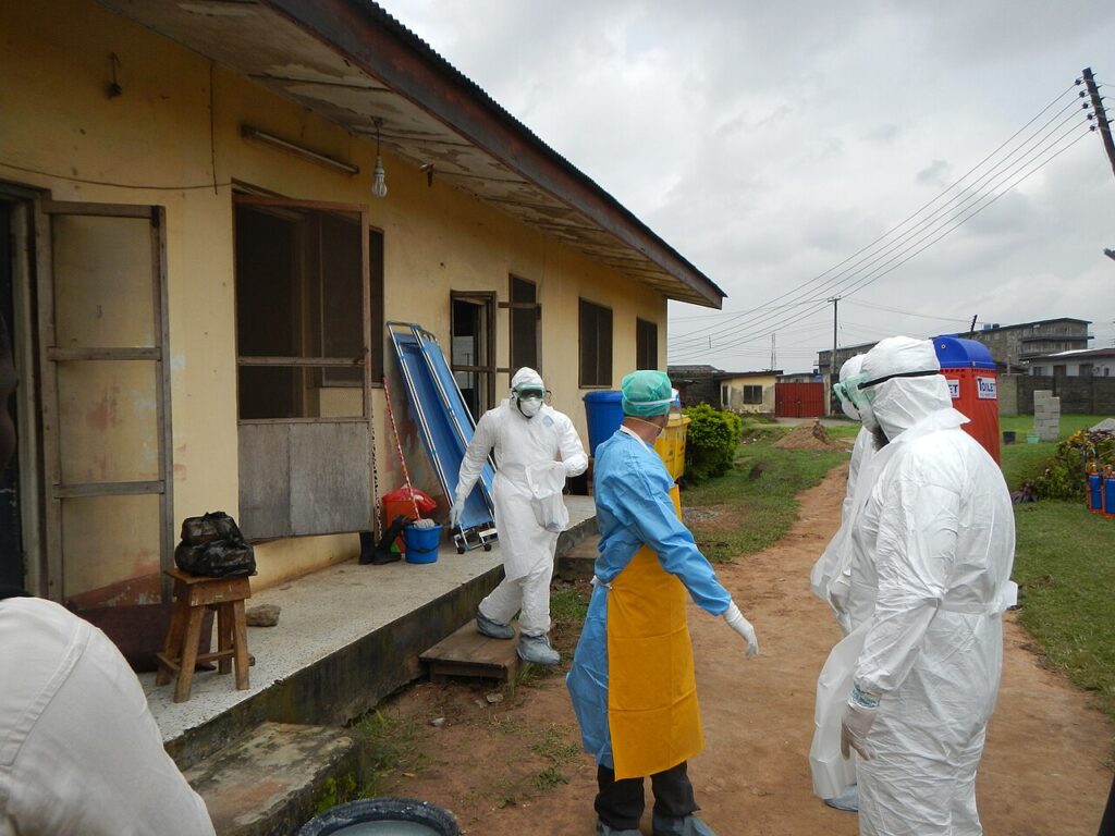 WHO health workers in protective gear outside an Ebola treatment unit.