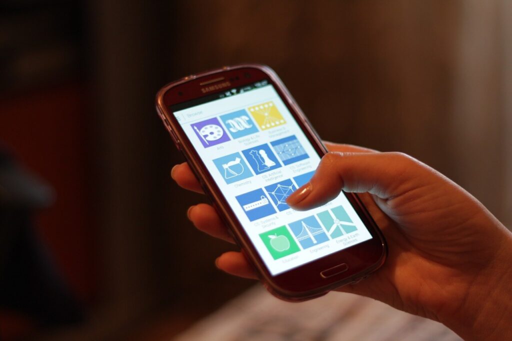 A hand tapping app icons on a smartphone screen — the kind of screen access China's AI assistants are fighting for